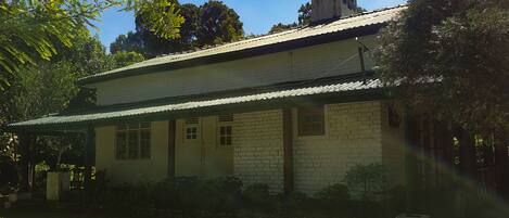 A two-story house with a brick exterior, a metal roof, and a covered porch.