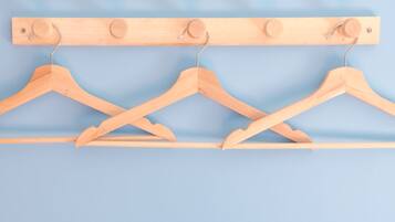 Three wooden hangers on a wooden rack against a blue background.
