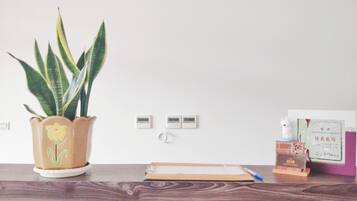 A desk with a potted plant, a notepad, a pen, a small bottle, and a card.