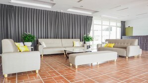 Una sala moderna con un sofá, dos sillones, una mesita de centro y plantas en macetas.
