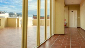 Un pasillo con ventanas amplias, suelo de baldosas y una puerta al final.
