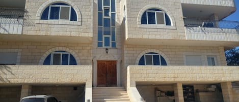 A multi-story building with a central entrance, two side entrances, and a staircase leading to the main entrance.