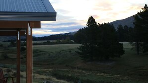 A rural landscape with a metal roofed structure, possibly a gazebo or pavilion, overlooking a field with trees and hills in the distance. - Alpine Views Burkes Pass (Burkes Pass)