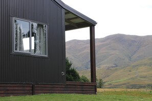 Un edificio moderno con un amplio ventanal y un porche con vistas a un paisaje montañoso.