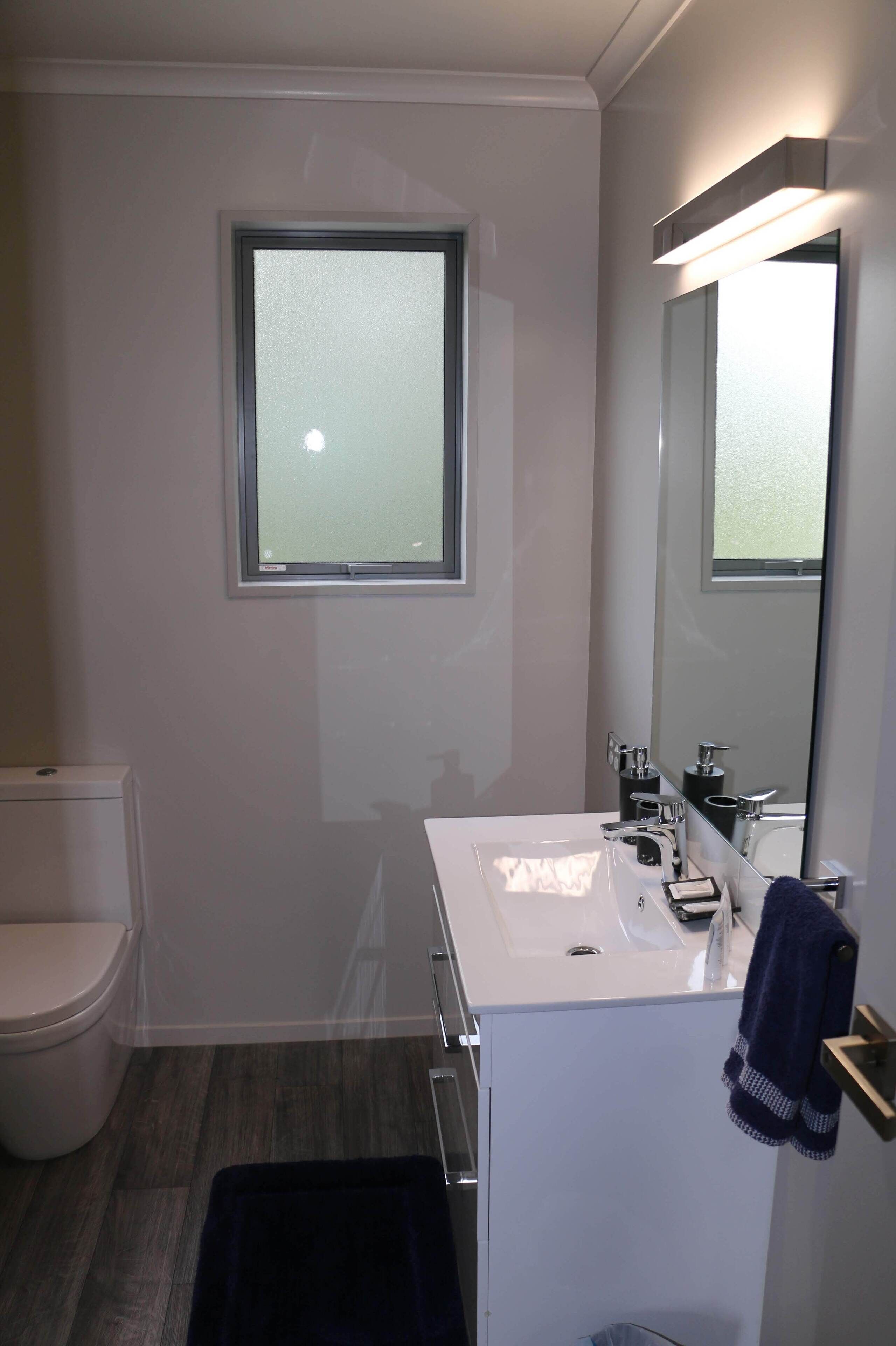 Ein modernes Badezimmer mit Toilette, Waschbecken und Spiegel.