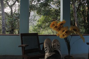A room with a wooden chair, a laptop, and a vase with flowers. - Mahagedara Home Stay (Laggala-Pallegama)