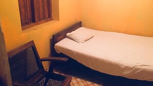 A small, single-bed room with a wooden headboard and a window with wooden blinds. - Mahagedara Home Stay (Laggala-Pallegama)