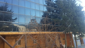 Un edifici modern amb finestres de vidre reflectant i una estructura de fusta al primer pla.