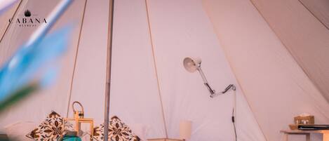 A tent with a bed, a lamp, and a lantern.