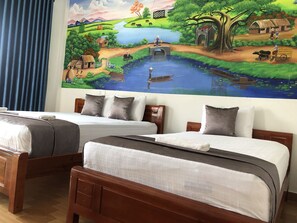 A hotel room with two wooden beds, each with a pillow and a blanket.