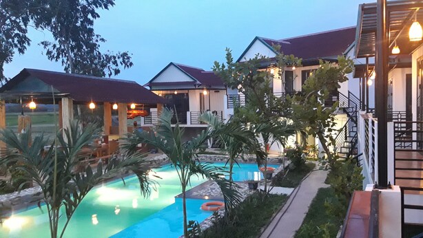 A resort with a swimming pool, multiple guest houses, and a well-lit outdoor area.