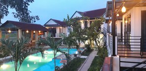 A resort with a swimming pool, multiple guest houses, and a well-lit outdoor area.