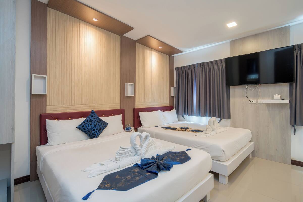 Una habitación de hotel con dos camas, un televisor de pantalla plana y un televisor montado en la pared.