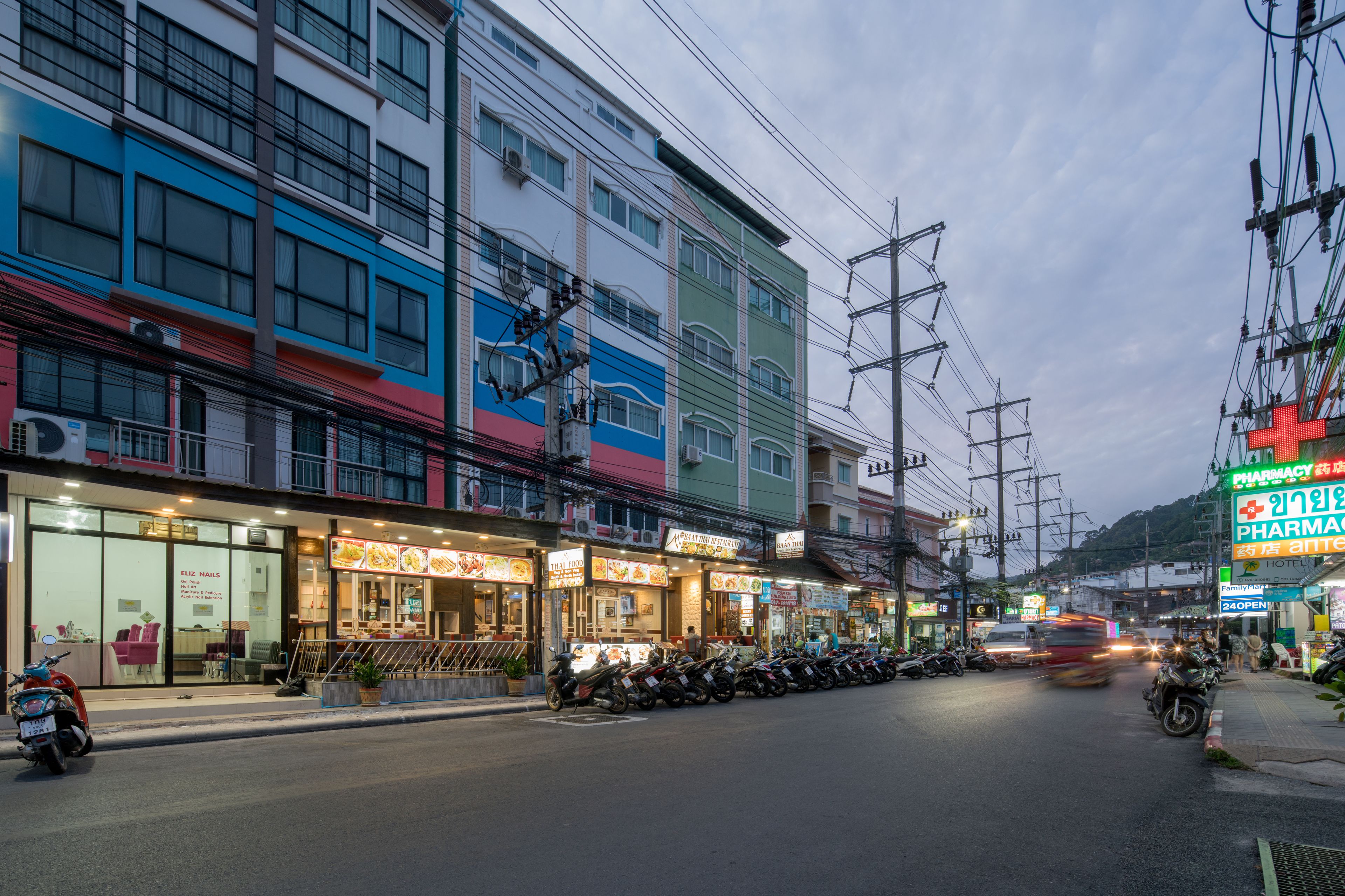 A multi-story building with various shops on the ground floor, including a pharmacy and a restaurant.