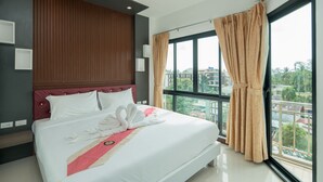 Quarto de hotel moderno com uma cama grande, cabeceira de madeira e vista da cidade através de amplas janelas.
