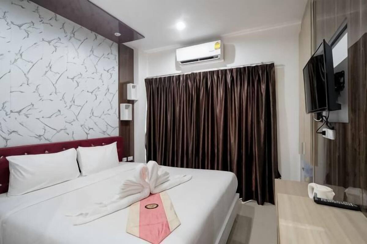 Una habitación de hotel con cama, televisión, aire acondicionado y cortina.