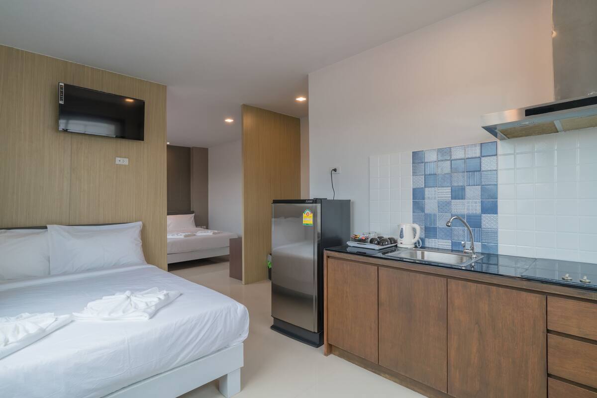 Habitación de hotel con cama, kitchenette y pequeño refrigerador.