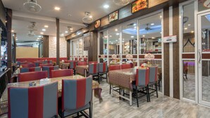 Um restaurante com cabines e mesas, piso de madeira e ventiladores no teto.