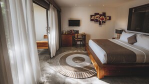 Une chambre à coucher avec un lit, un bureau, une chaise, un téléviseur et des œuvres d’art accrochées au mur.