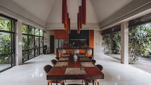 Un espace repas moderne avec une longue table en bois, de nombreuses chaises et un îlot central dans la cuisine.