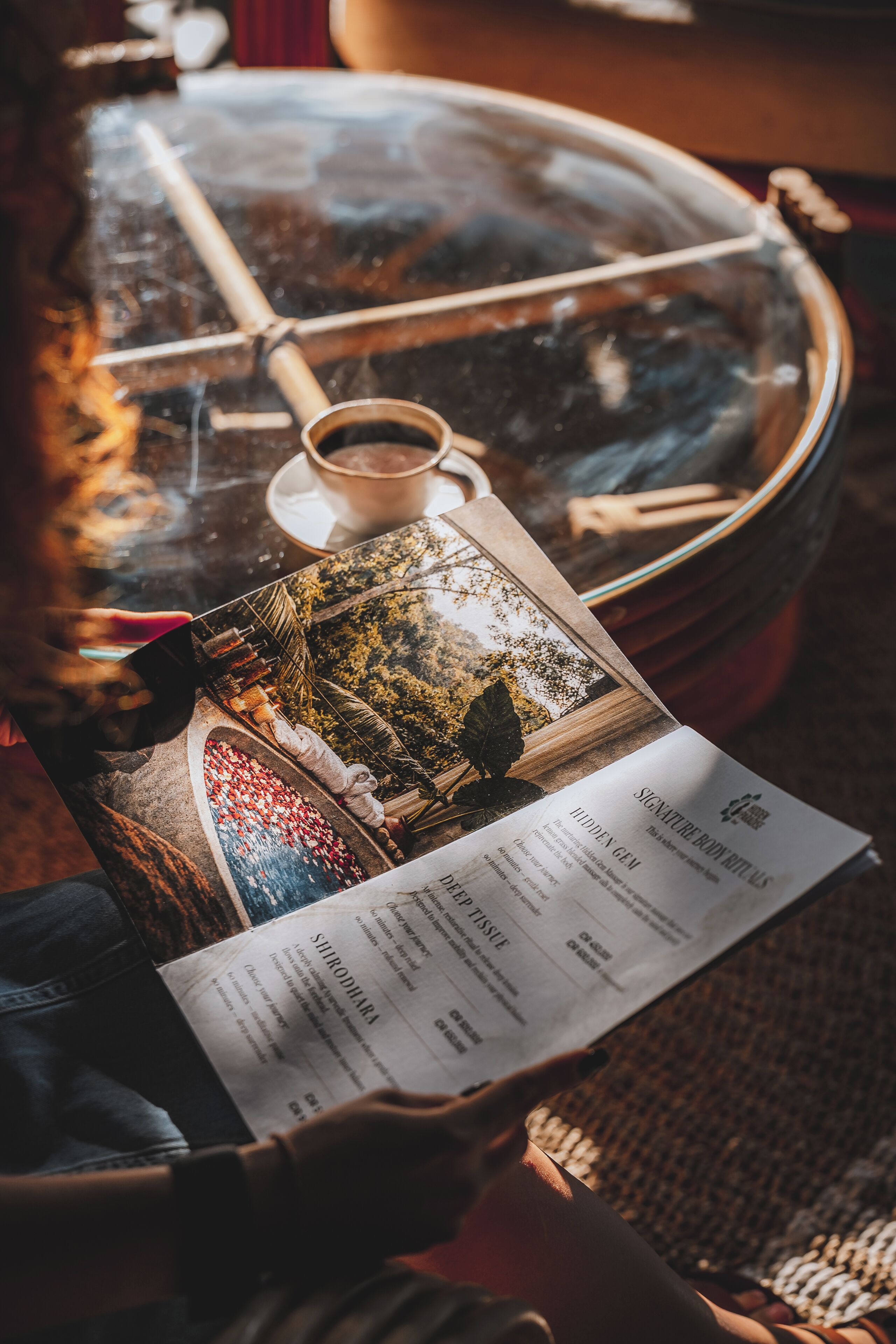 A table with a cup of coffee, a menu, and a book.