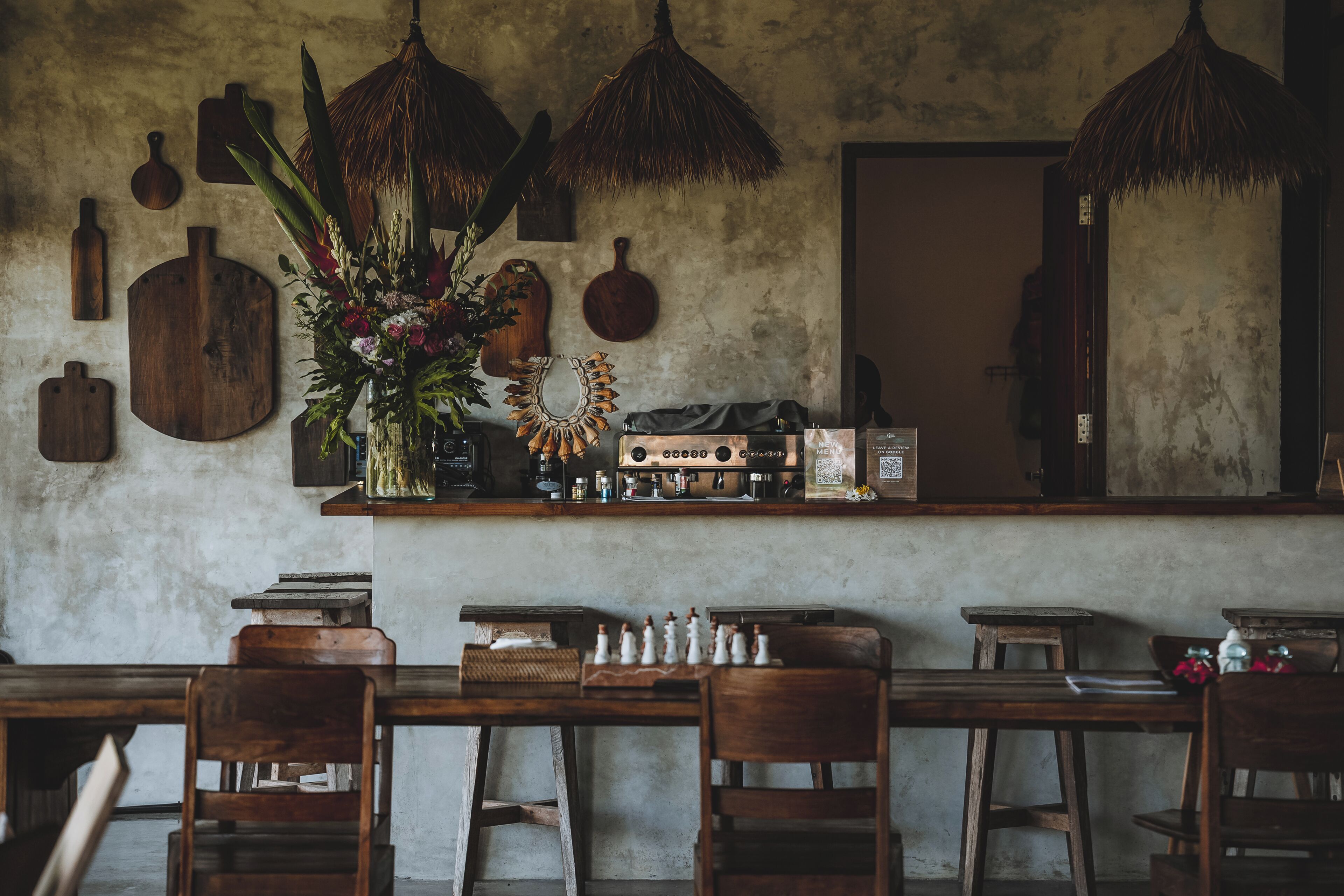 A rustic bar area with wooden furniture, a coffee machine, and a decorative plant.