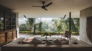 A modern living room with a sofa, a chair, and a ceiling fan.