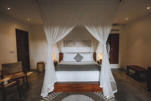 Un dormitorio con cama con dosel, una silla, una mesita de noche y una lámpara.