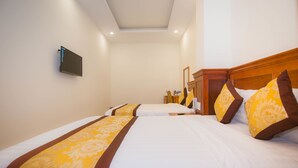 A hotel room with two beds, each with white bedding and yellow and brown decorative pillows. A flat-screen TV is mounted on the wall. - Hong Tung Hotel (Xuan Huong - Da Lat)