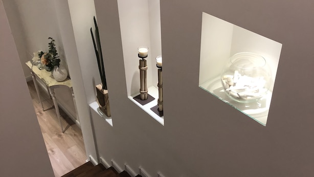 A staircase with dark wooden steps and white walls. There are three illuminated shelves with decorative items. - Edera e Camelie (Pompei)