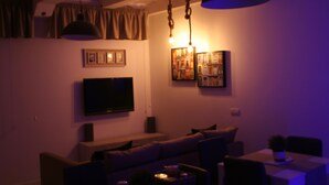 A dimly lit living room with a sofa, a flat-screen TV, and a dining table. - Edera e Camelie (Pompei)
