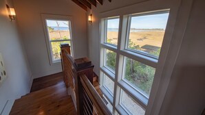 A staircase with wooden railings and large windows offering a view of a natural landscape. - 'Forcynthia' Luxury Bay Home 4BR/4.5BA ,w/ dock, kayak launch (St. George Island)
