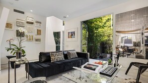 Un salon moderne avec un canapé en cuir noir, une table basse en verre et divers objets de décoration.