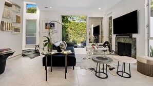 Un salon moderne avec un canapé noir, une table basse en verre et une cheminée.