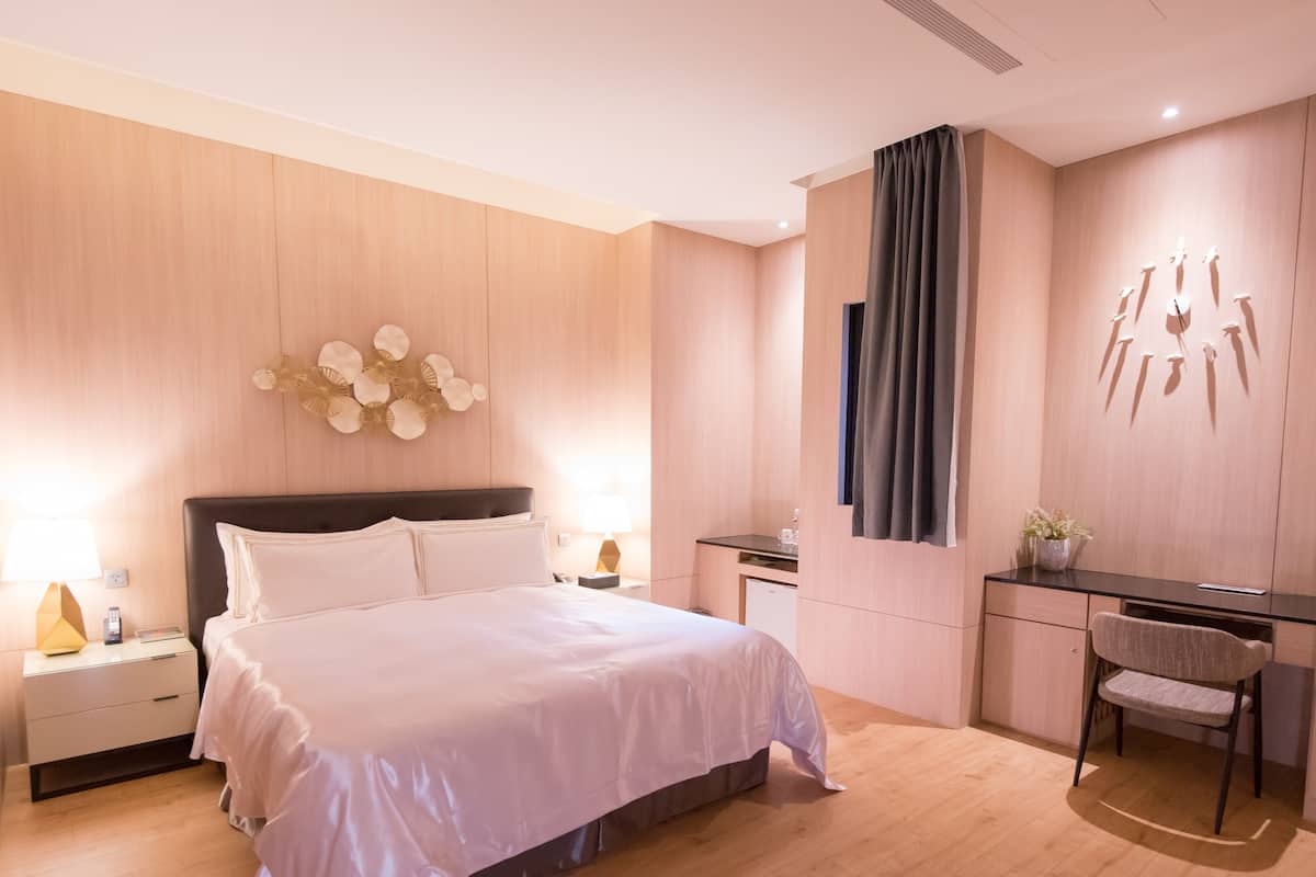 Ein modernes Schlafzimmer mit einem großen Bett, Nachttischen, einem Schreibtisch und einem Stuhl.