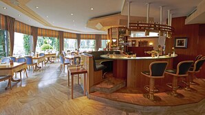 A spacious hotel lobby with a bar area, multiple seating arrangements, and large windows offering a view of greenery outside. - Rheinhotel LARUS (Kaltenengers)