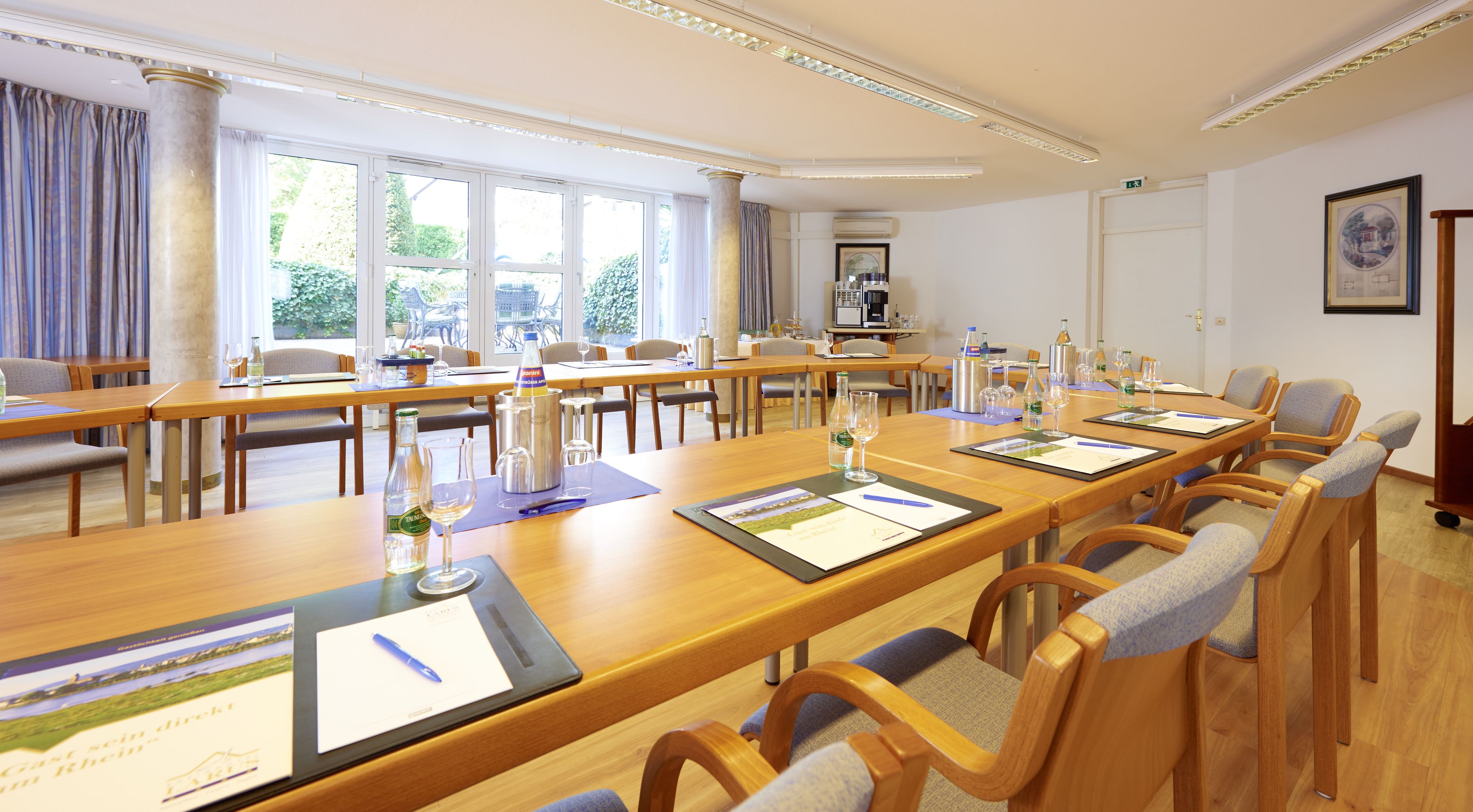 A conference room with long tables, chairs, and various items like wine glasses and bottles.