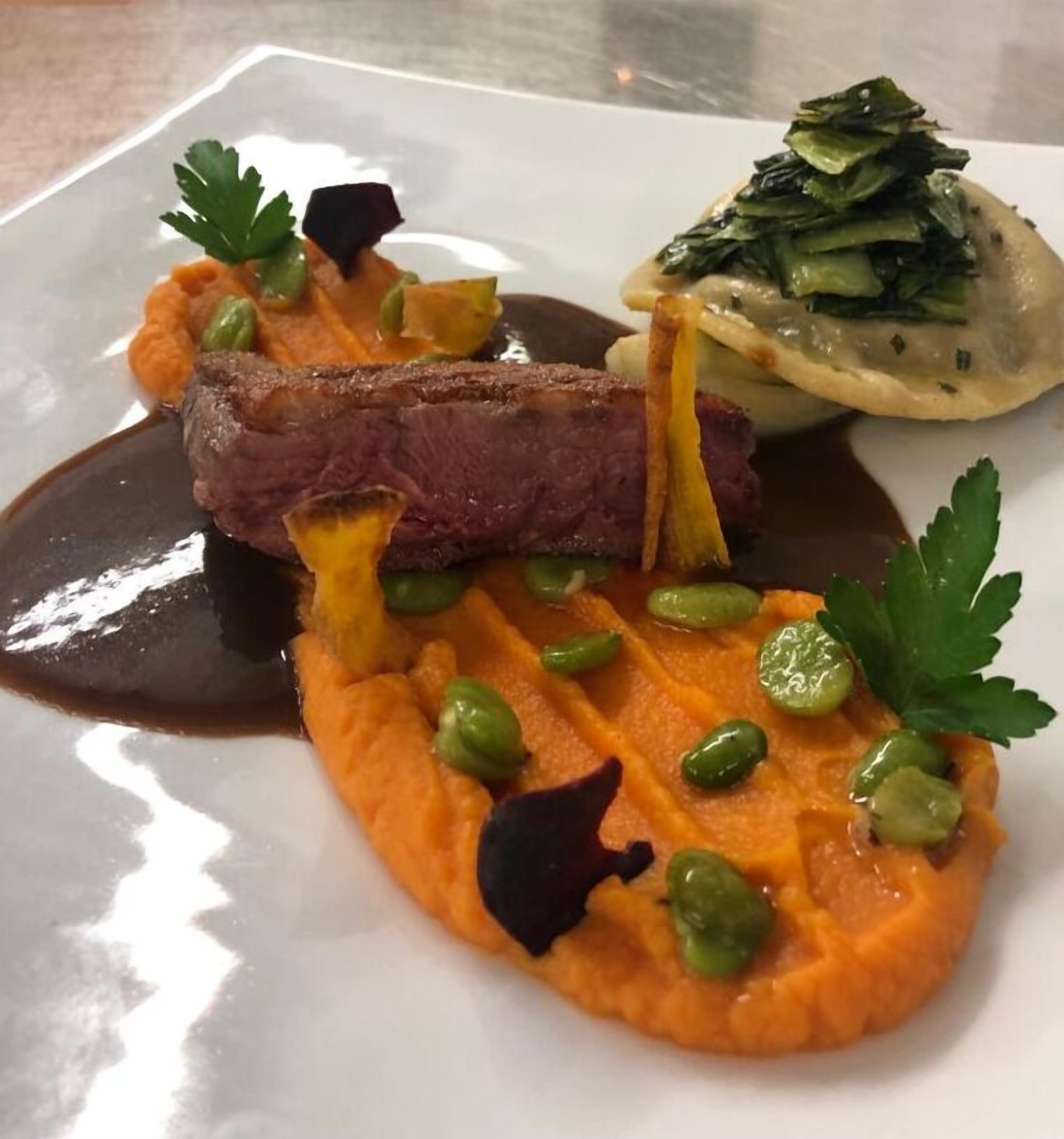 Ein Teller mit einem Steak, Kartoffelpüree, Erbsen und einem Salat.