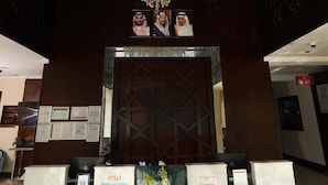 Un área de recepción con una araña, mostrador de recepción y diplomas enmarcados en la pared.