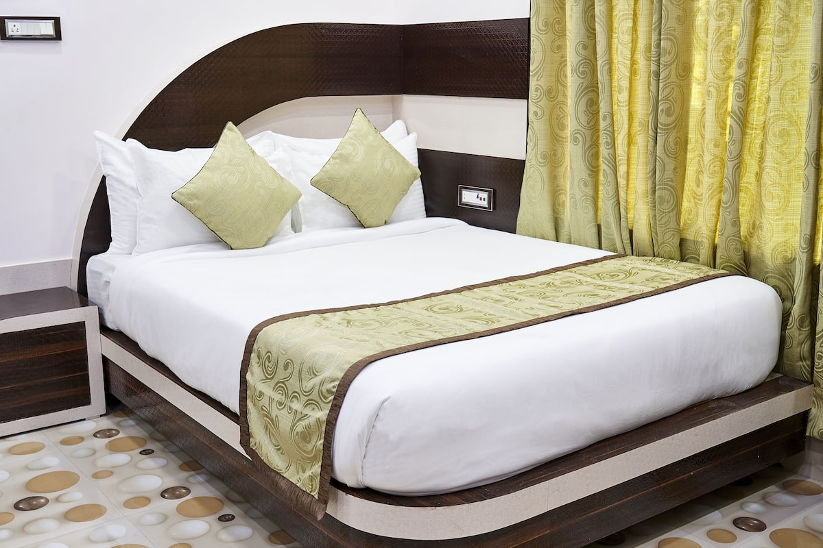 Una cama bien hecha con una colcha blanca y verde, dos almohadas y un cabecero de madera.