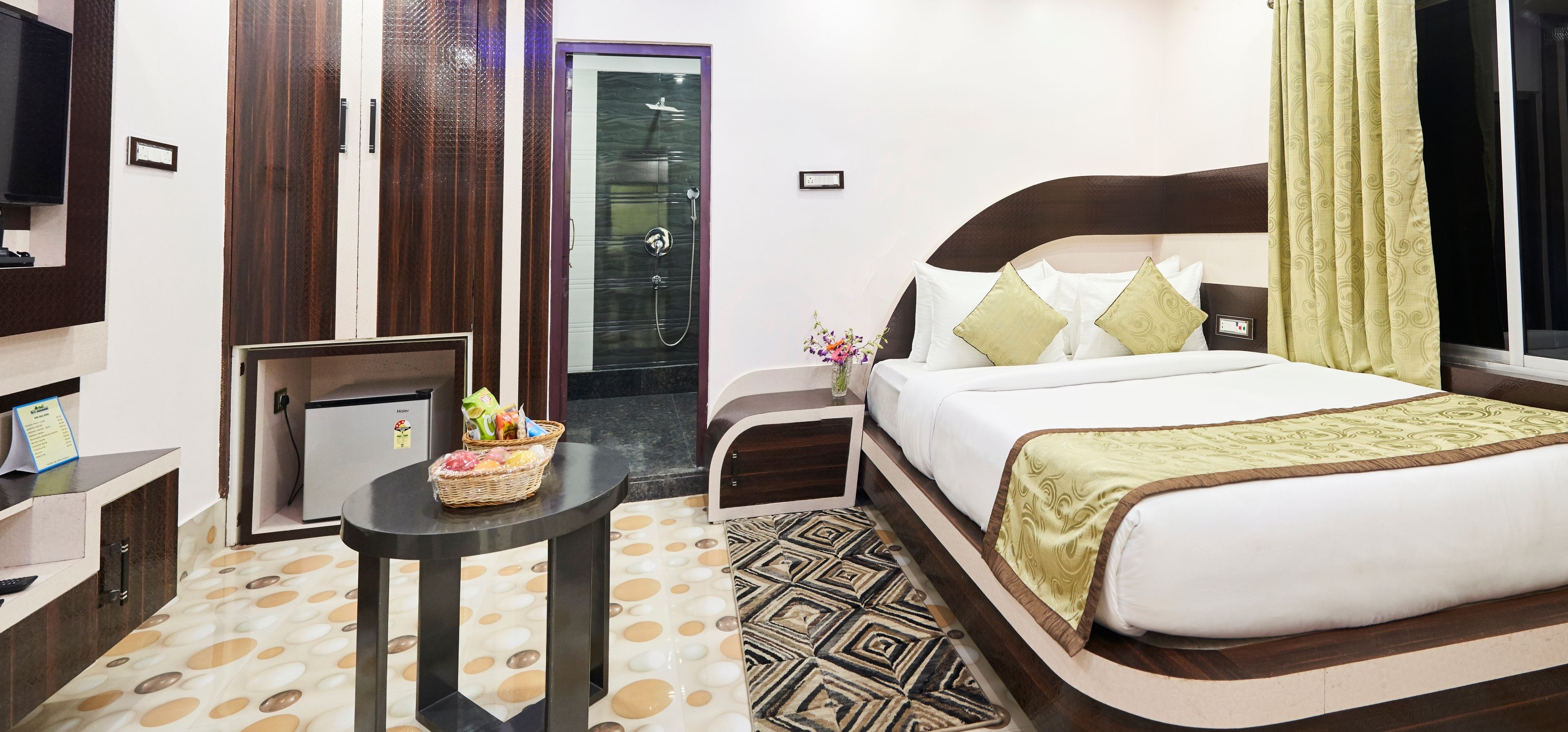 Una habitación de hotel con cama, una mesita con una cesta, un televisor y un armario.