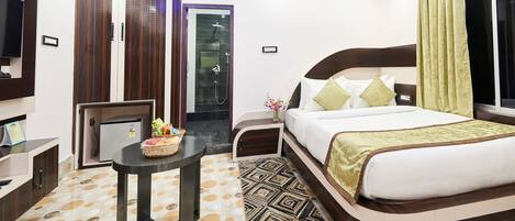 Una habitación de hotel con cama, una mesita con una cesta, un televisor y un armario.