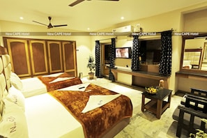 A hotel room with two beds, a TV, a desk, and a ceiling fan.