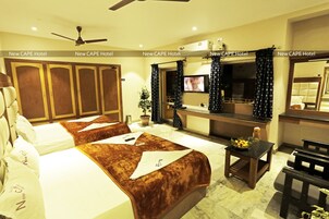 A hotel room with two beds, a TV, a desk, and a ceiling fan.