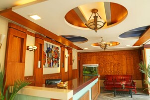 A reception area with a wooden reception desk, a red sofa, a fish tank, and a chandelier.
