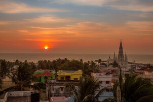 A coastal cityscape at sunset with a prominent church and colorful buildings.