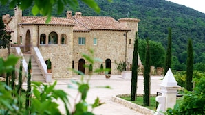 A stone building with a tiled roof, a staircase, and a garden with cypress trees. - Relais Tenuta del Gallo (Amelia)