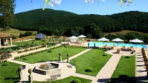 A landscaped garden with a swimming pool, outdoor seating, and a fountain. - Relais Tenuta del Gallo (Amelia)