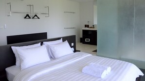 Una habitación de hotel moderna con una cama grande, un cabecero oscuro y un diseño minimalista.