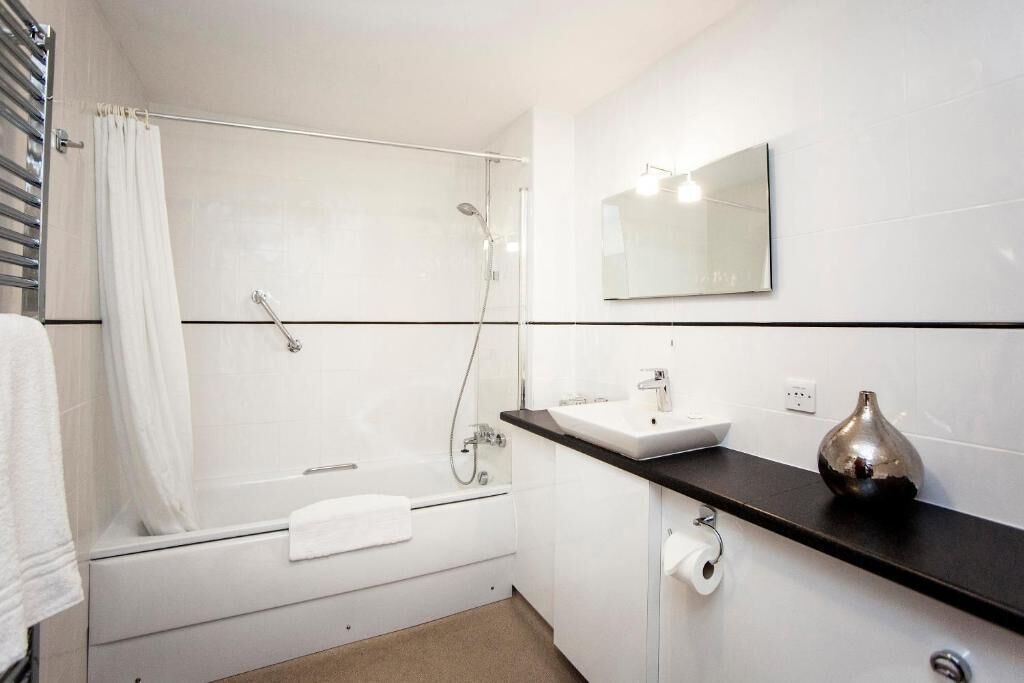 A modern bathroom with a bathtub, shower, and sink.